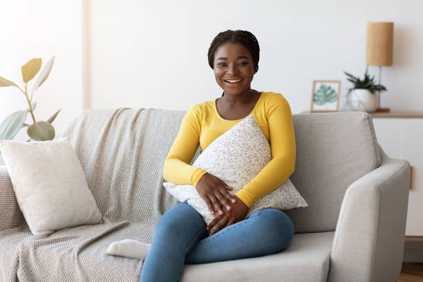 istock Day At Home. Smiling Black Woman Sitting On Comfortable Couch With Pillow 1316605036