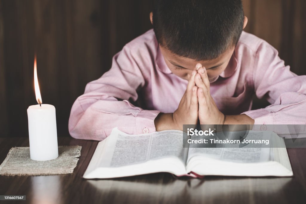 boy praying to God. Hands folded in prayer concept for faith,spirituality and religion. Boys Stock Photo