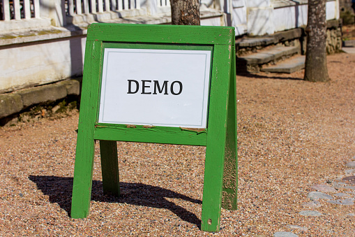 A green wooden sign showing that it is time for a software demo, website demo, app demo or any other type of demonstration of something.