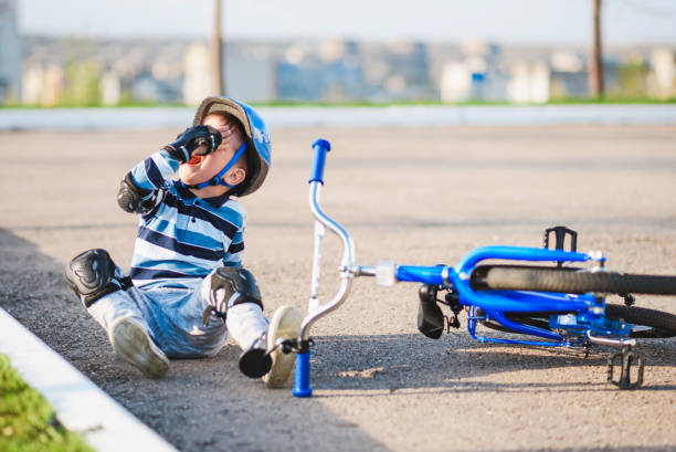 un petit enfant est tombé d’un vélo sur la route, pleurant et hurlant de douleur. - child bicycle cycling danger photos et images de collection