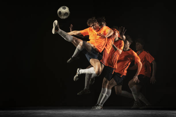 joven jugador de fútbol masculino en movimiento y acción con luz mixta sobre fondo oscuro. - stroboscopic image fotografías e imágenes de stock