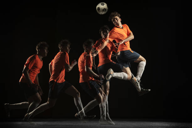 Young male football soccer player in motion and action in mixed light on dark background. Forward. Young caucasian football soccer player playing in motion in mixed light on dark background. Concept of healthy lifestyle, professional sport, action, motion, hobby, team. temporal aliasing stock pictures, royalty-free photos & images