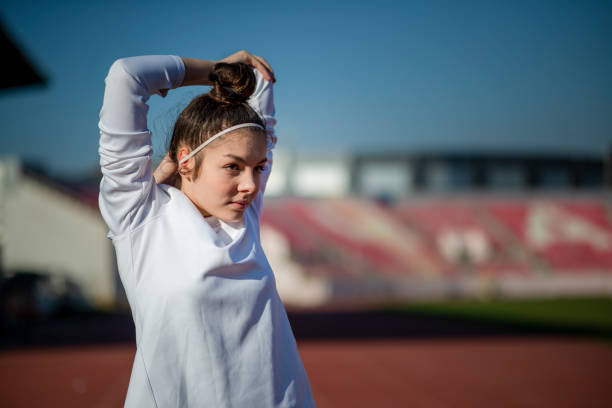 mujer joven que se estira antes del entrenamiento - track and field athlete women vitality speed fotografías e imágenes de stock