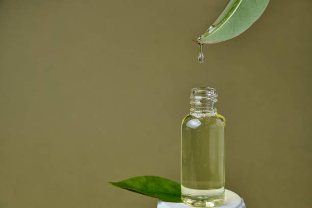 istock essential oil dripping from leaf into glass bottle isolated on beige 1316624550