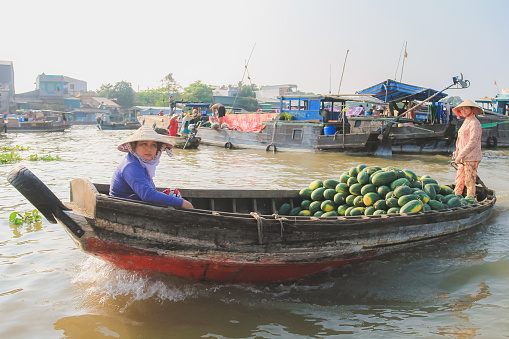 Lively bustling floating market with commerce between traditional sampan boats along the Hau (Bassac) River at the Mekong Delta at Can Tho, Vietnam.