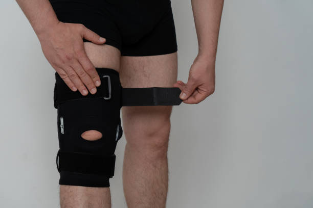 istock Leg support. A man adjusts a black orthosis on his leg. Copspace 1316624854