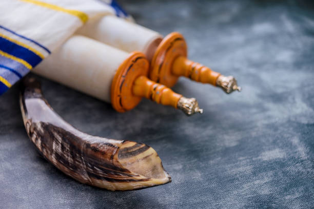 istock Jewish holidays in a synagogue prayer items with prayer shawl tallit shofar, torah scroll on soft focus 1316626656