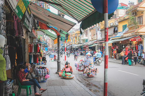 Local Vietnamese people and city life along the bustling, colourful streets and shopfronts of downtown central Hanoi, Vietnam.