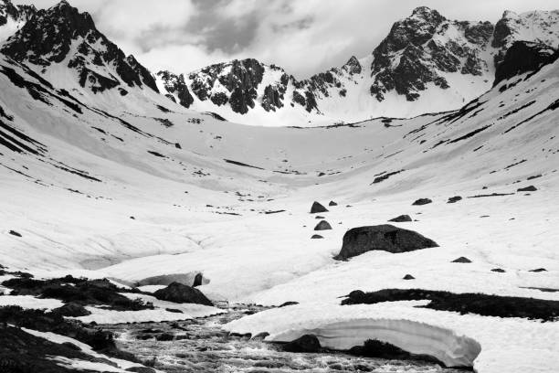 Photo of River with snow bridges in high snowy mountains at spring evening