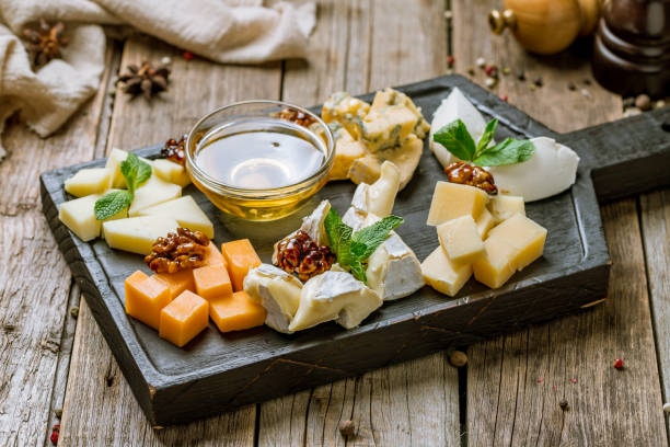 Cheese plate italian food with honey, mint and walnuts on beautiful wooden board on old wooden table stock photo