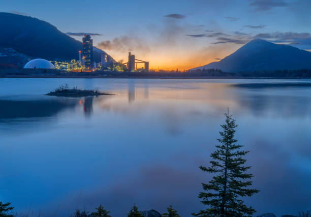 Lac des Arcs and the Exshaw Cement Plant Sunrise at Lac des Arcs and the Exshaw cement plant in Alberta, Canada cement factory stock pictures, royalty-free photos & images