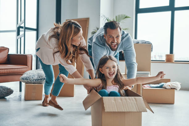 Cheerful young family Cheerful young family smiling and unboxing their stuff while moving into a new apartment cheerful stock pictures, royalty-free photos & images