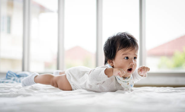 chéri asiatique jouant avec à la maison - être étendu sur le ventre photos et images de collection