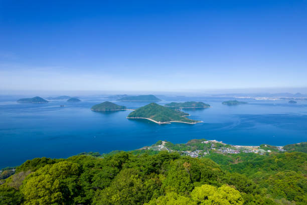 una foto de drones de principios del verano del monte shiude, famoso por sus flores de cerezo y el mar interior de seto en la ciudad de mitoyo, prefectura de kagawa. - sky sea town looking at view fotografías e imágenes de stock