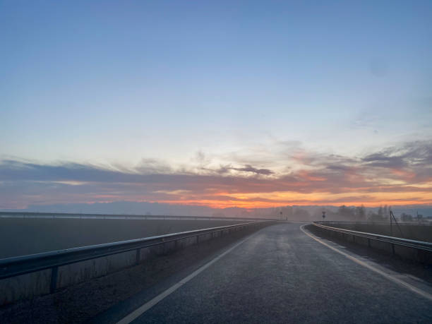 istock Highway at sunset with red sky and fog. 1316642927