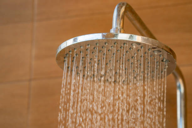 屋外シャワーヘッドに近づくと、リゾートプールに飛び込む前に冷たい水を体にシャワーします。 - hotel clean home interior bathroom ストックフォトと画像