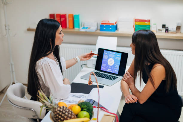 Dietologist showing the presentation about how digestive system works to her patient, during their consultation about her food intolerance
