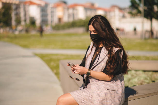istock Young woman with face mask using her smart phone 1316648677