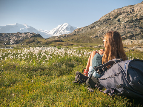 Female hiker relaxes on meadow near alpine lake