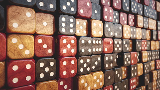 Side view on a set of dark multi-colored diverse wooden gambling dice arranged in a large stack