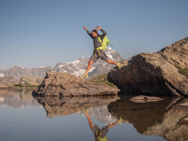 istock Man jumps from rock to rock on alpine lake 1316649962