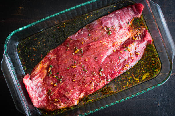 marinando el filete del flanco en un plato de vidrio - marinated fotografías e imágenes de stock