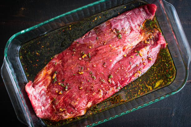 Marinating Flank Steak in a Glass Dish A raw flank steak marinating in a glass baking dish marinated photos stock pictures, royalty-free photos & images