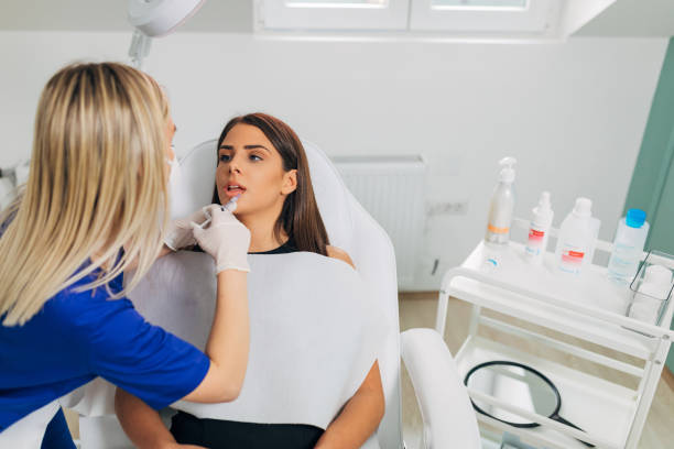 istock Expertised plastic surgeon, performing the lips fillers injection on the young female client, while using hyaluronic fillers 1316652778