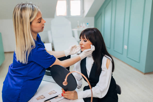 istock Beautician lifting the client face so she can have the insight how her face will look after botox treatmant 1316653110