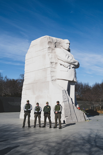 Washington DC, USA - January 22, 2021: Four National Park Service law enforcement personnel stand beside the large sculpture at the Martin Luther King Memorial in Washington DC.