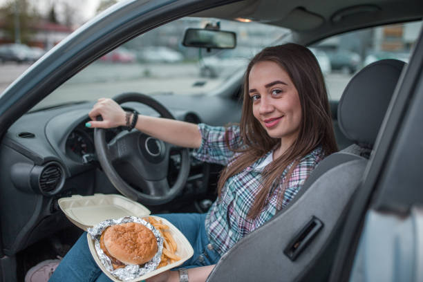 istock Happy woman eating burger in her car 1316654600