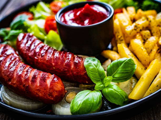 salsicce fritte e verdure su tavolo di legno nero - sausage knackwurst food bratwurst foto e immagini stock