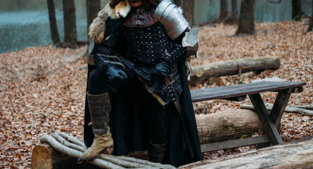 istock Medieval knight with sword in armor in the forest.holds the sword.a man in armor, with a wolf cloak. costume games 1316657176