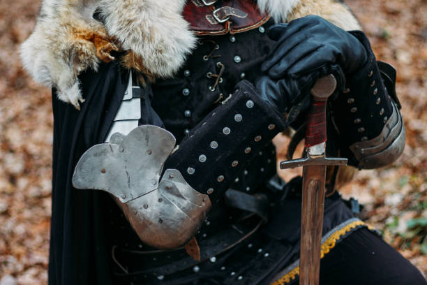 istock Medieval knight with sword in armor in the forest.holds the sword a man in armor, with a wolf cloak. costume games 1316657699