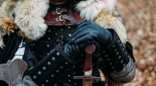 istock Medieval knight with sword in armor in the forest.holds the sword a man in armor, with a wolf cloak. costume games 1316657705