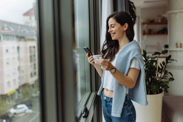 istock Female reading one message over the phone, while standing in front of window. 1316658965