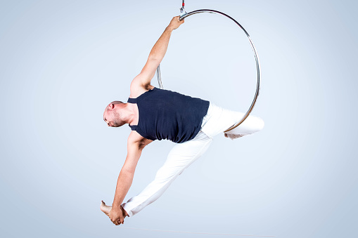 A man performs a trapeze routine with a ring