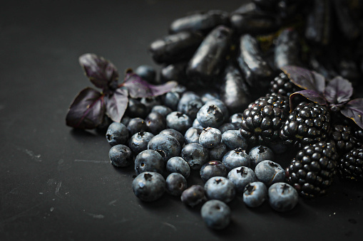 Dark fruits on a black background. Blueberries, Purple /Black grapes, blackberries, and purple basil.