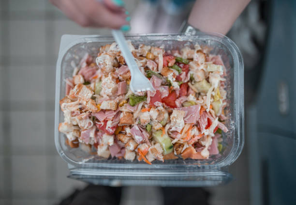 Young business woman on a break eating healthy salad from plastic container box