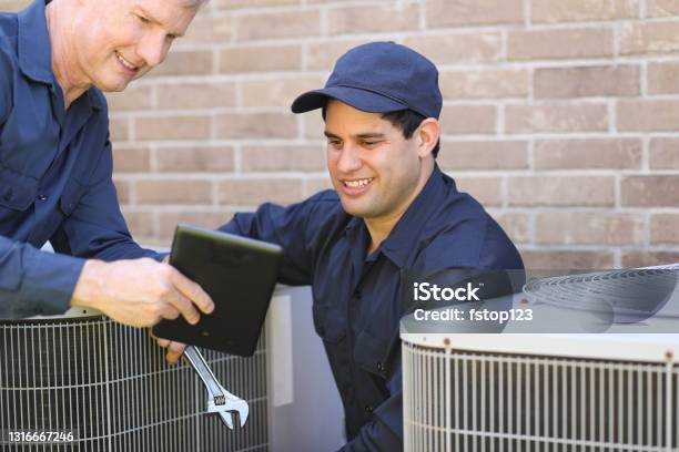 Multiethnic Team Of Blue Collar Air Conditioner Repairmen At Work Stock Photo - Download Image Now