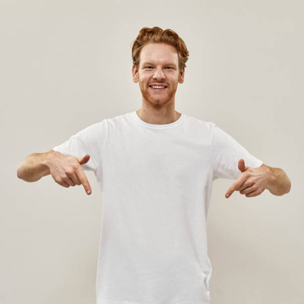istock Young redhead man smiles and points with fingers down 1316668547