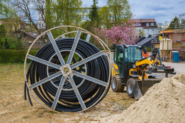 istock Cable for electric power supply on wooden spool on a construction site. Small yellow excavator. 1316671463