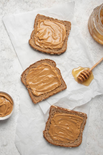 Peanut butter sandwich with honey Flat lay of Peanut butter on slices of wheat bread with honey. peach color table stock pictures, royalty-free photos & images