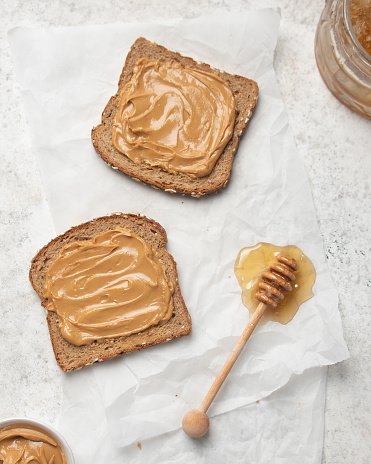 Flat lay of Peanut butter on slices of wheat bread with honey.