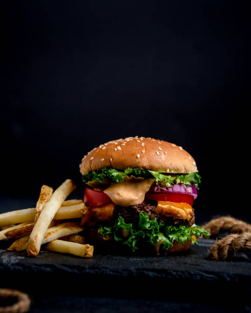 close-up de hambúrguer com fundo preto - burger french fries cheeseburger hamburger - fotografias e filmes do acervo