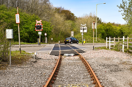 Bridgend, Wales - April 2021: Single railway track crossing a main road on the Waterton Industrial Estate in Bridgend. The line was originally used to transport engines from the Ford Motor Company factory.