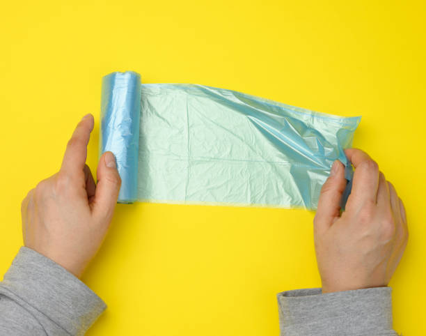 istock female hand unwinds a blue plastic bag for rubbish, yellow background 1316674726