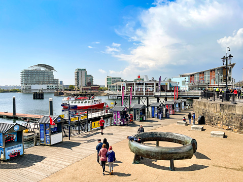 Cardiff Bay, Wales - May 2021: People on the waterfront promenade of Mermaid Quay in Cardiff Bay.