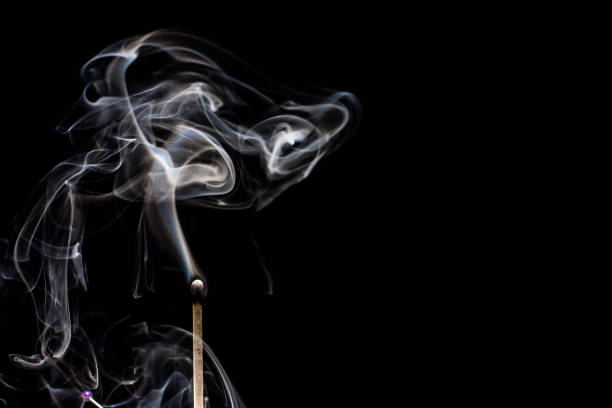 Smoking matchstick on black background. Plenty of copy space.