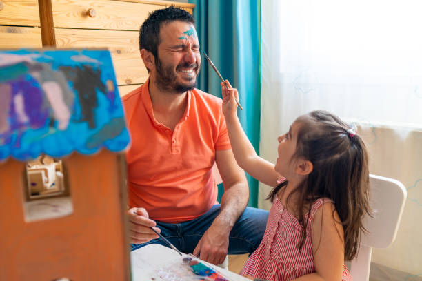 istock Young father smiling with eyes closed while his face is painted by his little daughter 1316680449